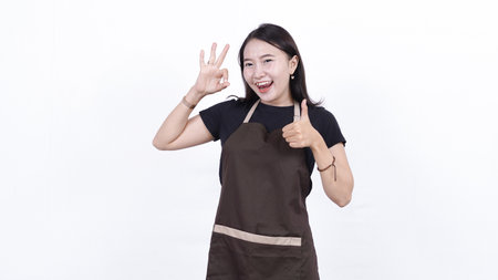 asian woman shopkeeper OK gesture isolated blue backgroundの写真素材