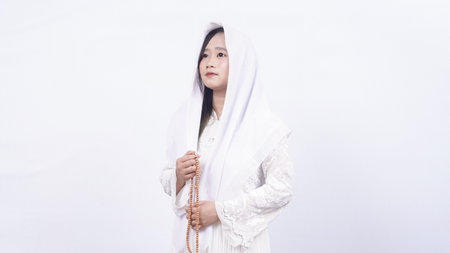 Asian muslim woman wearing prayer beads pray with tasbih in white backgroundの写真素材