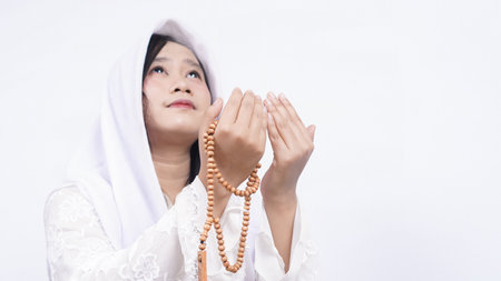 Asian muslim woman wearing prayer beads pray in white backgroundの写真素材