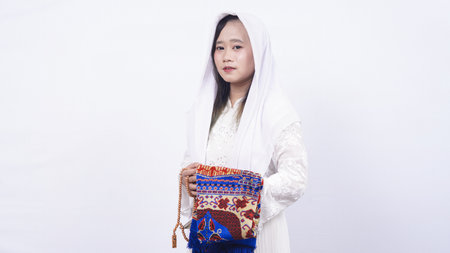 Asian muslim woman wearing prayer beads and prayer mat in white backgroundの写真素材
