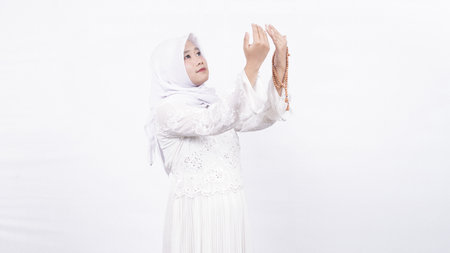 Asian muslim woman wearing prayer beads pray in white backgroundの写真素材
