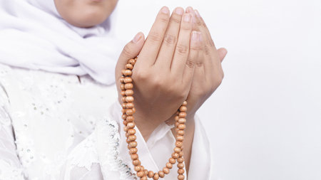 Asian muslim woman wearing prayer beads pray in white background