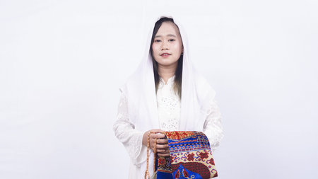 Asian muslim woman wearing prayer beads and prayer mat in white background