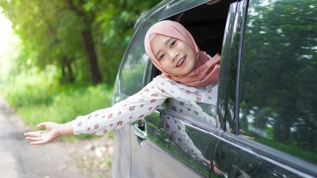portrait of happy woman wearing hijab travelling with a carの写真素材