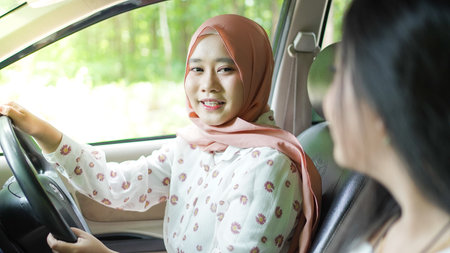 portrait of happy woman wearing hijab travelling with friend in carの写真素材