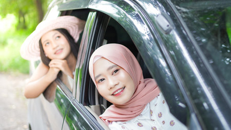 portrait of happy woman wearing hijab travelling with friend in carの写真素材