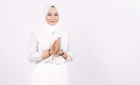 Asian muslim woman wearing prayer beads welcoming guests or Ied Fitr Greeting in white backgroundの写真素材