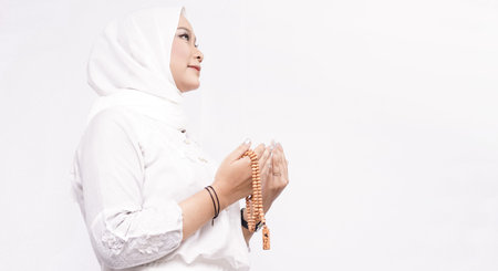Asian muslim woman wearing prayer beads pray in white background