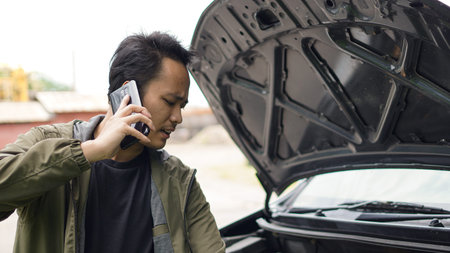 Asian man opened the hood of the car while callingの写真素材