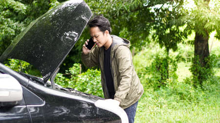 Asian man opened the hood of the car while callingの写真素材
