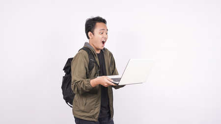 The young man wearing bag shouting and yelling on a white background with laptopの写真素材