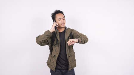 Asian man called out while looking at a watch on a white backgroundの写真素材