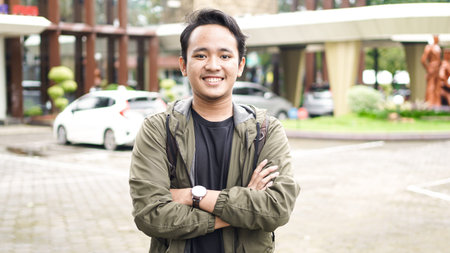 Portrait of smiling Asian man with backpack standing and staring at the camera