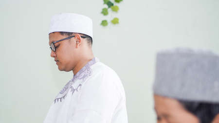 a Muslim family consisting of parents and children perform greeting movements during prayerの写真素材