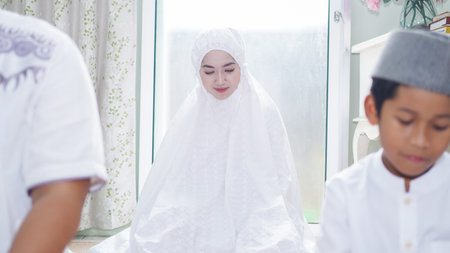 a Muslim family consisting of parents and children perform greeting movements during prayerの写真素材