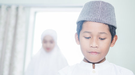 a Muslim family consisting of parents and children prayingの写真素材