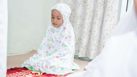 a Muslim family consisting of parents and children perform greeting movements during prayerの写真素材
