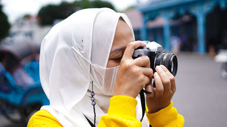 an Asian woman traveler in keraton solo wearing jilbab and analog cameraの写真素材