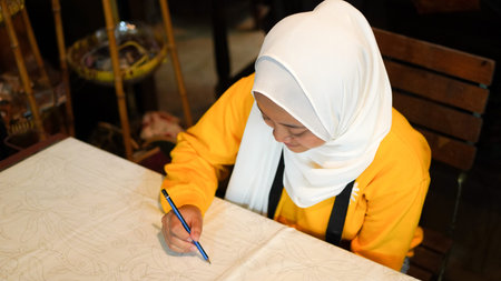Asian women learn to make batik wearing jilbab and analog cameraの写真素材