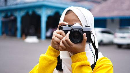 an Asian woman traveler in keraton solo wearing jilbab and analog camera