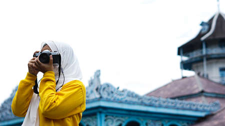 an Asian woman traveler in keraton solo wearing jilbab and analog cameraの写真素材