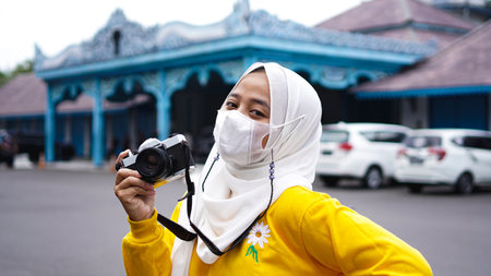 an Asian woman traveler in keraton solo wearing jilbab and analog cameraの写真素材