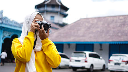 an Asian woman traveler in keraton solo wearing jilbab and analog cameraの写真素材