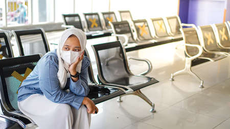 Asian women are tired of waiting at the station wearing jilbab and analog cameraの写真素材