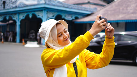 Asian female traveling taking selfies at the keraton solo wearing jilbab and analog cameraの写真素材