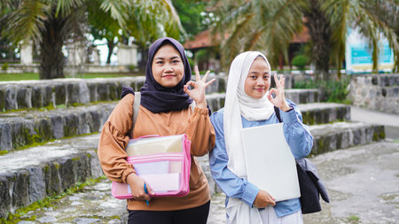 two asian woman students friend walking on campus with ok gestureの写真素材