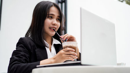 Asian business woman dringking coffe and working with his laptop at cafeの写真素材