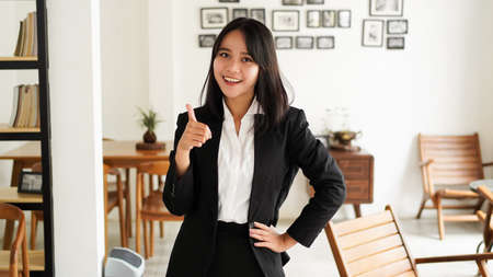 Beautiful young asian business woman in suit and okay finger hands up at officeの写真素材