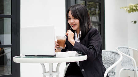 Asian business woman dringking coffe and working with his laptop at cafeの写真素材