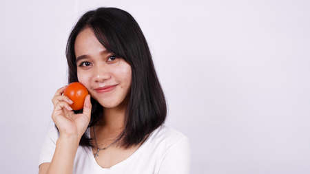 Close up beautiful asian women with a tomato isolated on white backgroundの写真素材