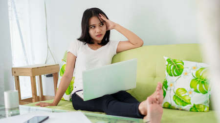 Stressed Asia woman work from home with computer at homeの写真素材