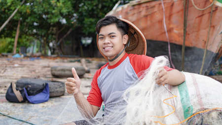 Portrait of a young male fisherman preparing a fishing net in beachの写真素材