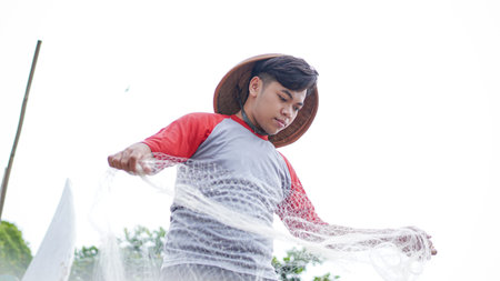 Portrait of a young male fisherman preparing a fishing net in beachの写真素材