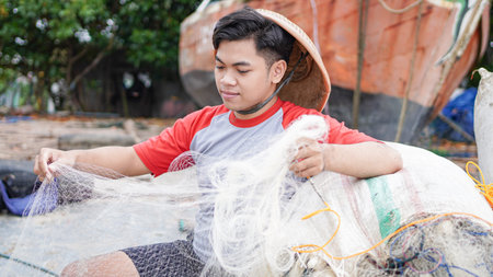 Portrait of a young male fisherman preparing a fishing net in beachの写真素材