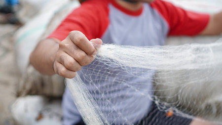 Portrait of a young male fisherman preparing a fishing net in beach