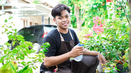Asian man taking care watering flower at home gardenの写真素材