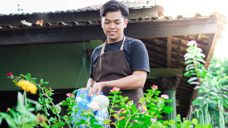 Asian man taking care watering flower at home garden
