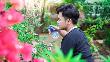 Asian man taking care watering flower at home garden
