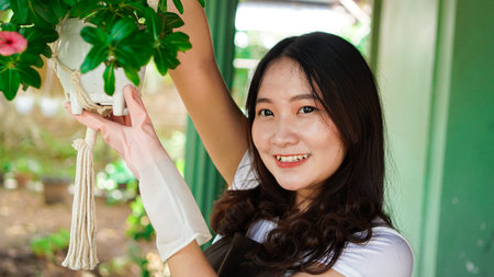 Asian woman hanging plants at home make beautiful decorationの写真素材