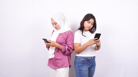 two asian girls playing the phone isolated with white background
