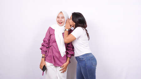 two asian women whisper whisper isolated white backgroundの写真素材