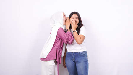 two asian women whisper whisper isolated white backgroundの写真素材