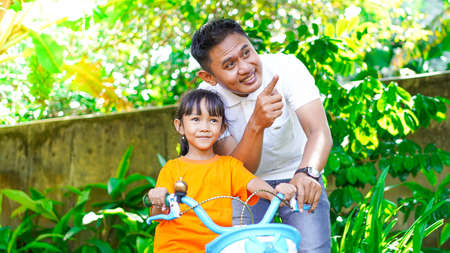 father and daughter playing bicycles in the parkの写真素材