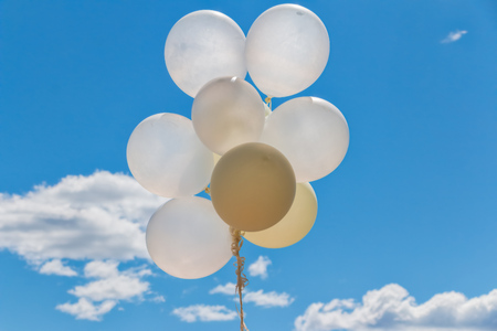 white balloons against blue summer sky with cloudsの写真素材