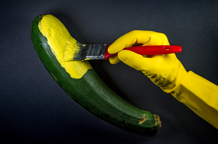 human hand painting a zucchini yellow to look like a bananaの写真素材
