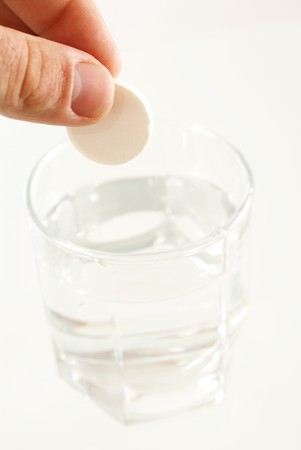 Tablet of sedative in a hand above a glass with water の写真素材